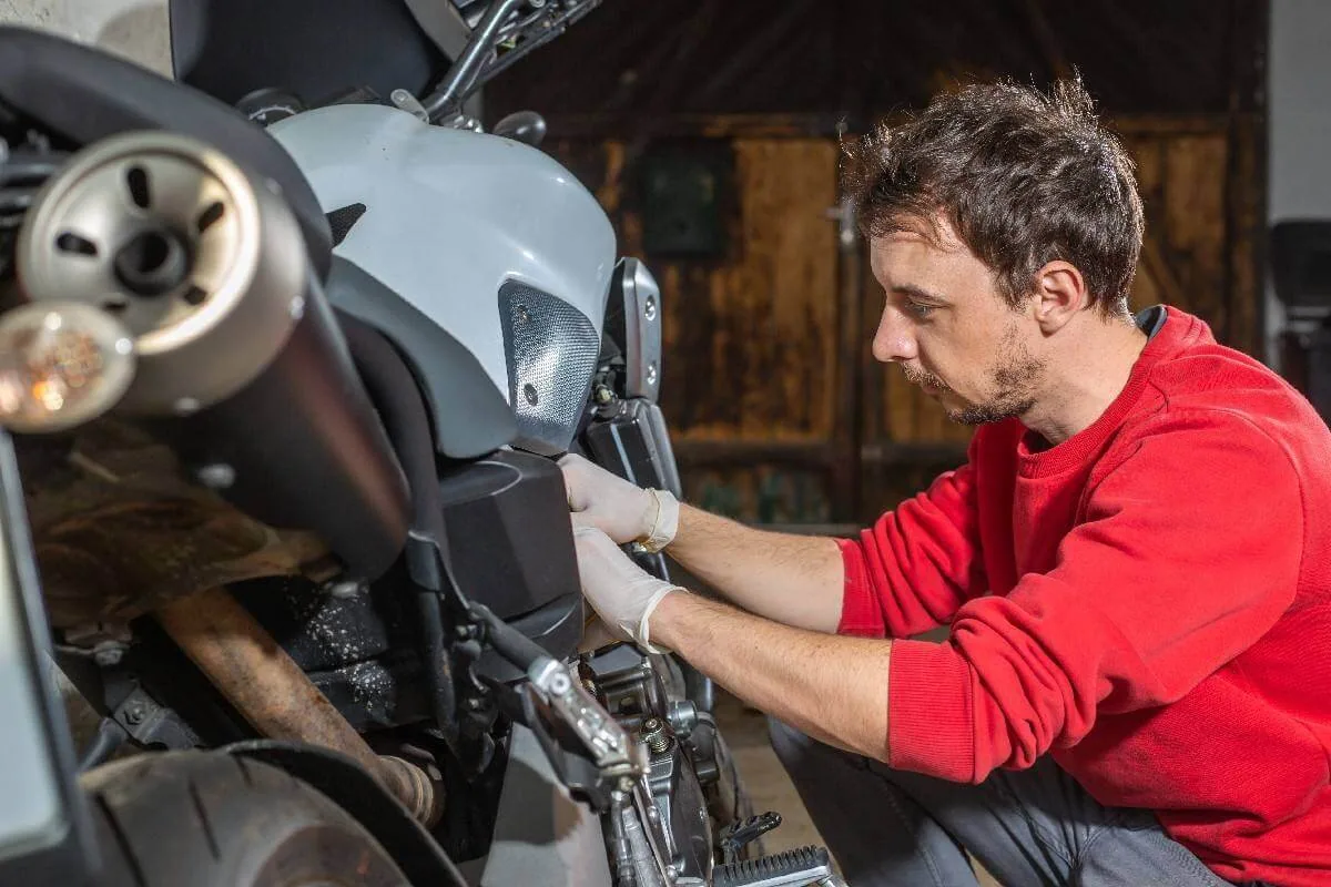 Persona realizando tareas de mantenimiento en una motocicleta